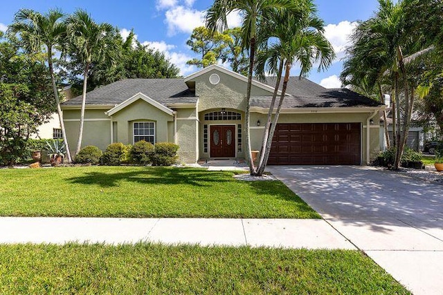 1112 Wild Cherry Ln, Wellington, FL 33414 - ranch-style home with stucco siding, a front lawn, an attached garage, and driveway
