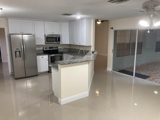 1112 Wild Cherry Ln, Wellington, FL 33414 - kitchen with dark stone countertops, appliances with stainless steel finishes, white cabinetry, and a ceiling fan