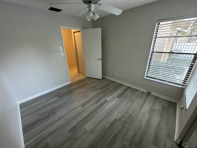 unfurnished bedroom with visible vents, a textured ceiling, baseboards, and wood finished floors