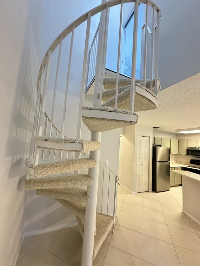 staircase featuring tile patterned floors, a textured ceiling, and baseboards