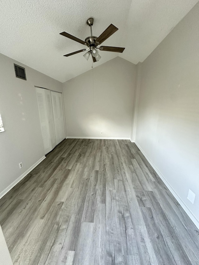 unfurnished bedroom featuring vaulted ceiling, visible vents, a closet, and wood finished floors
