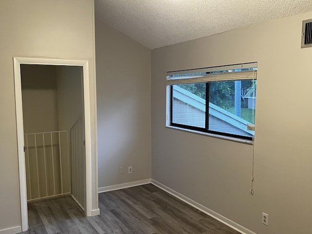 unfurnished bedroom featuring visible vents, a textured ceiling, baseboards, and dark wood-style flooring
