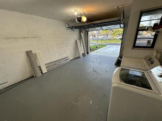 garage featuring concrete block wall, a garage door opener, and washing machine and clothes dryer