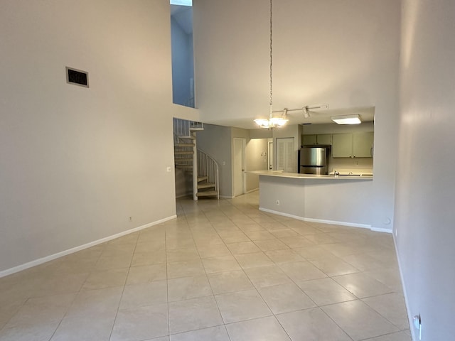 kitchen featuring visible vents, freestanding refrigerator, a peninsula, light tile patterned floors, and baseboards