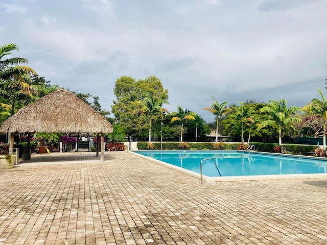 community pool with a gazebo, a patio area, and fence