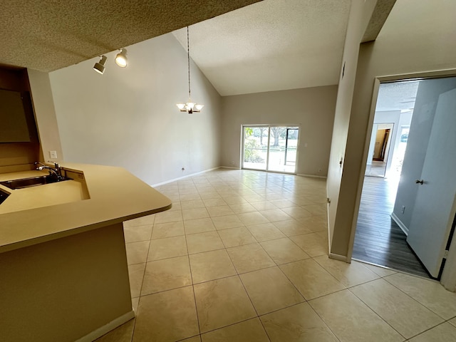 unfurnished dining area featuring light tile patterned floors, baseboards, a sink, a textured ceiling, and a notable chandelier