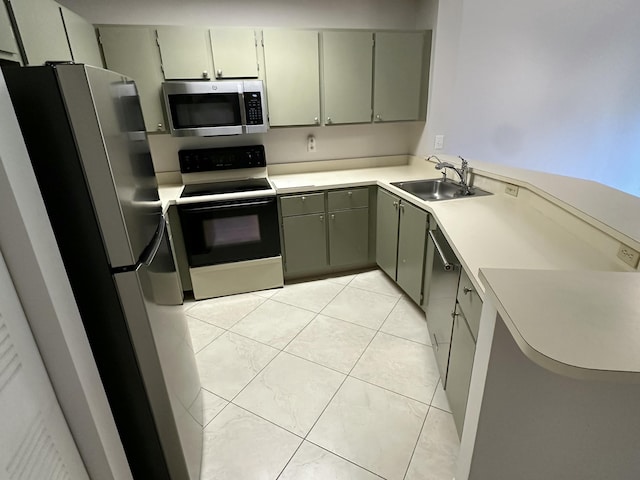 kitchen with light countertops, light tile patterned floors, gray cabinets, appliances with stainless steel finishes, and a sink