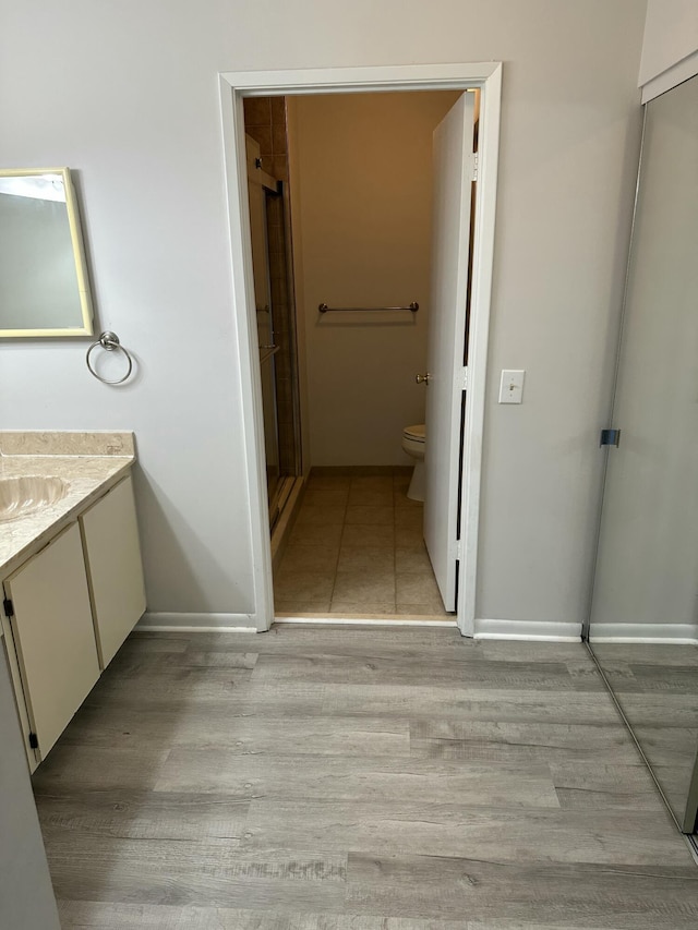 full bathroom featuring vanity, wood finished floors, baseboards, a shower stall, and toilet