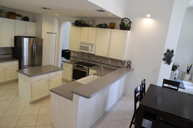 kitchen featuring appliances with stainless steel finishes, arched walkways, dark countertops, backsplash, and a center island