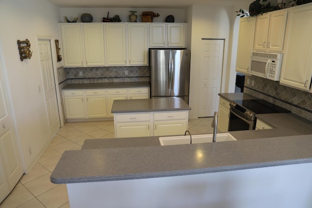 kitchen featuring stainless steel appliances, light tile patterned floors, backsplash, and dark countertops