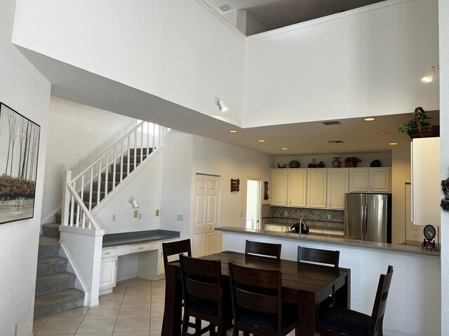 dining space featuring a high ceiling, stairs, and light tile patterned floors