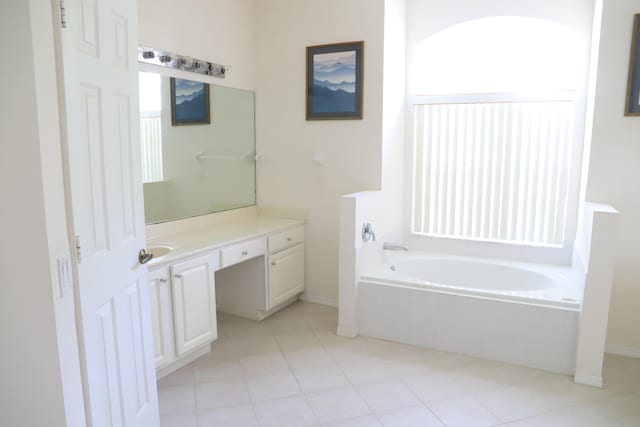bathroom featuring vanity, a bath, tile patterned flooring, and baseboards