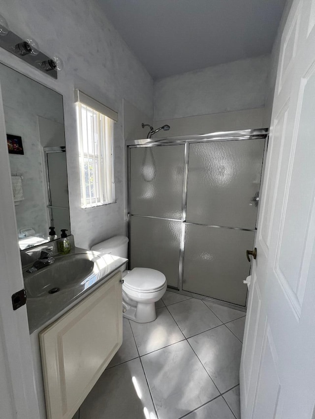 full bath featuring a stall shower, vanity, toilet, and tile patterned flooring