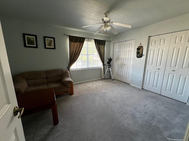 sitting room with ceiling fan, a textured ceiling, baseboards, and carpet