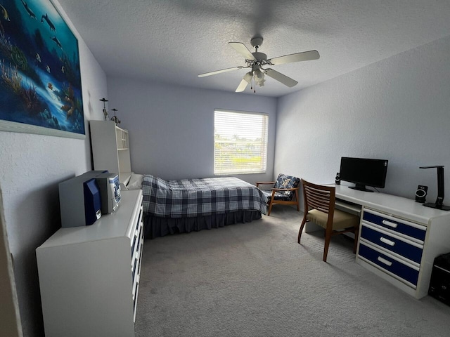 bedroom with carpet flooring, a textured ceiling, a desk, ceiling fan, and a textured wall