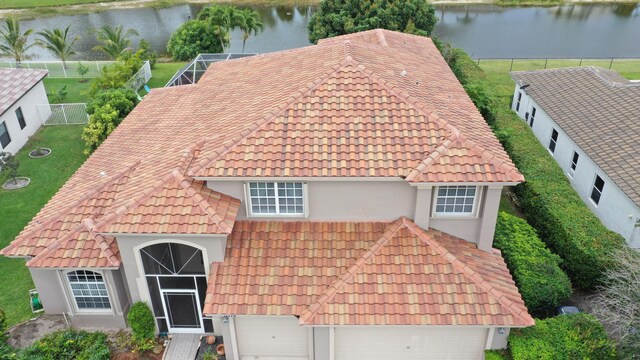 view of front of property featuring a tiled roof, a water view, stucco siding, and a garage