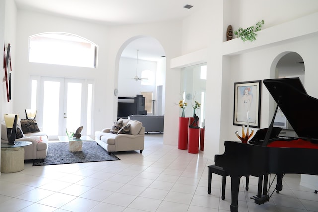 living area with a high ceiling, arched walkways, french doors, and tile patterned floors