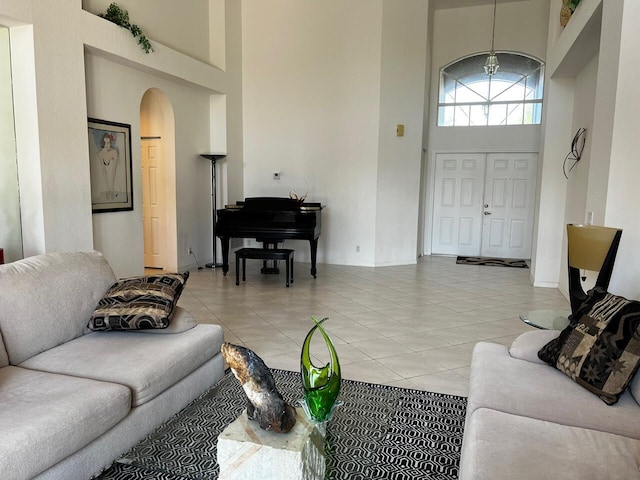 living room with a towering ceiling, arched walkways, and light tile patterned floors