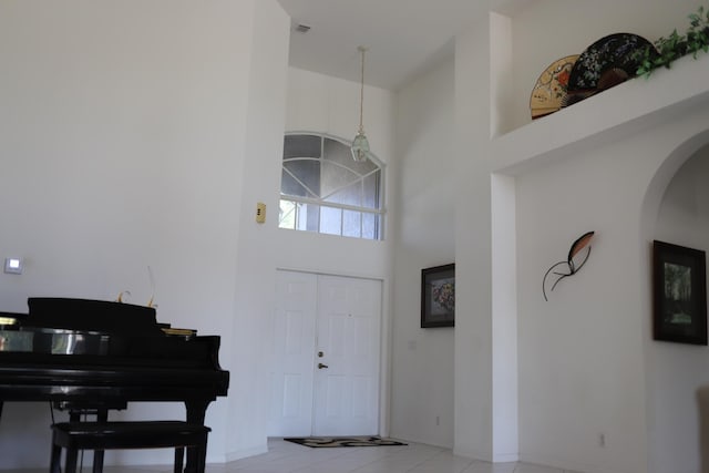 tiled entrance foyer with a towering ceiling, arched walkways, and baseboards