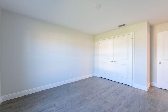2372 SW Import Dr, Port Saint Lucie, FL 34953 - unfurnished bedroom with wood finished floors, baseboards, a closet, and visible vents
