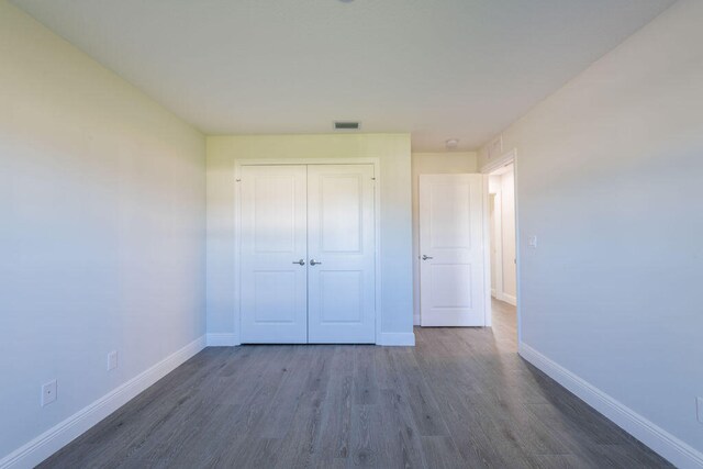 2372 SW Import Dr, Port Saint Lucie, FL 34953 - unfurnished bedroom with a closet, baseboards, dark wood finished floors, and visible vents