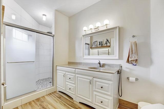 bathroom featuring vanity, a shower stall, toilet, and wood finished floors
