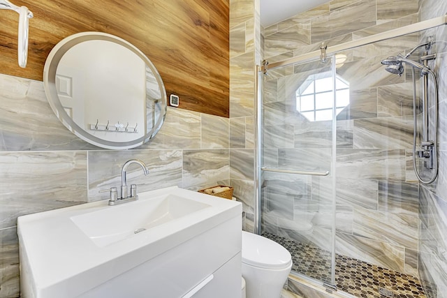 bathroom featuring toilet, tile walls, a stall shower, and vanity