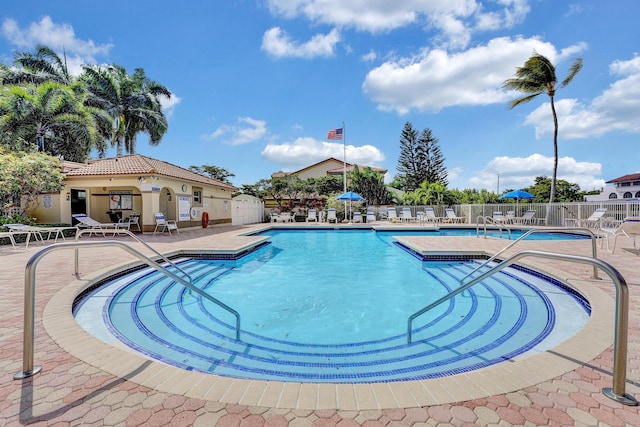 community pool with a patio and fence