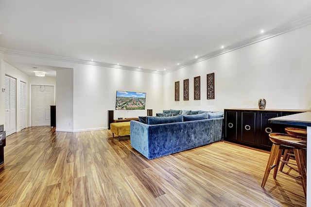 living area featuring crown molding, light wood-style flooring, and baseboards