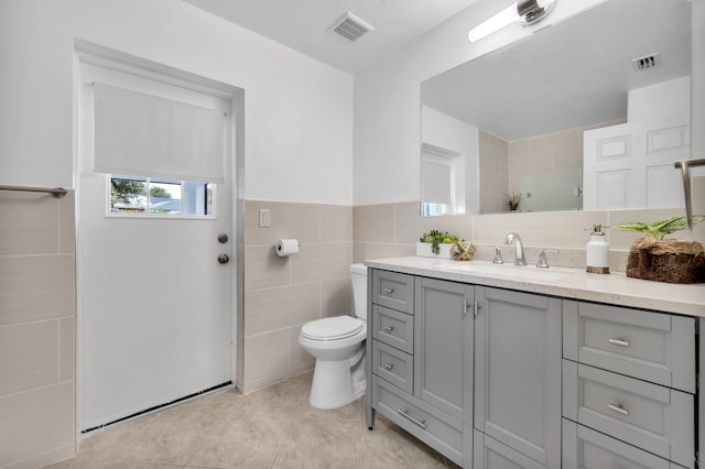 1355 SW Porter Rd, Port Saint Lucie, FL 34953 - bathroom featuring a tile shower, toilet, vanity, visible vents, and tile walls