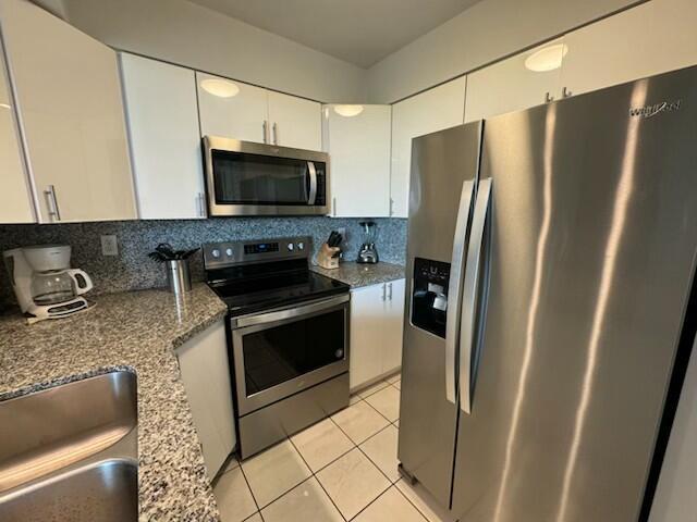 2075 SW 122nd Ave Unit 513, Miami, FL 33175 - kitchen featuring white cabinetry, decorative backsplash, light tile patterned floors, and stainless steel appliances