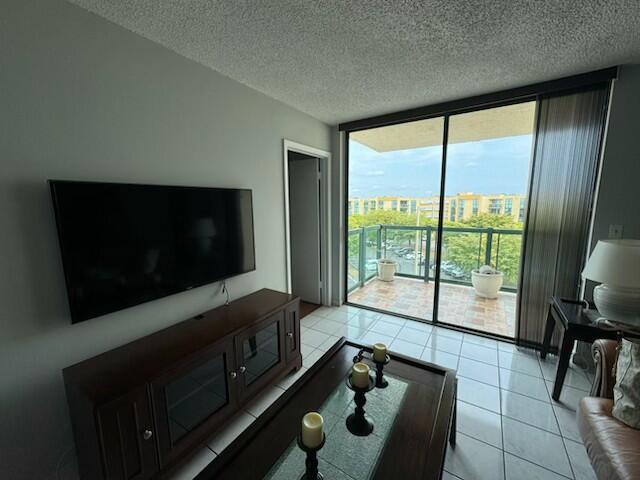 2075 SW 122nd Ave Unit 513, Miami, FL 33175 - living room with a textured ceiling, floor to ceiling windows, and light tile patterned floors