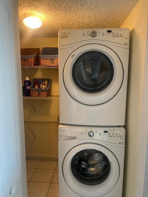 2075 SW 122nd Ave Unit 513, Miami, FL 33175 - laundry room with laundry area, a textured ceiling, stacked washing maching and dryer, and tile patterned flooring