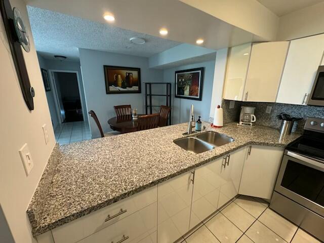 2075 SW 122nd Ave Unit 513, Miami, FL 33175 - kitchen with white cabinetry, a sink, light stone countertops, and appliances with stainless steel finishes