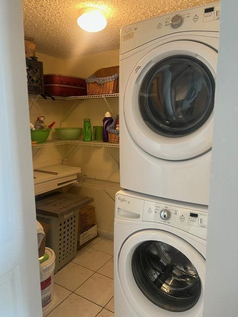 2075 SW 122nd Ave Unit 513, Miami, FL 33175 - laundry room with light tile patterned flooring, stacked washing maching and dryer, laundry area, and a textured ceiling