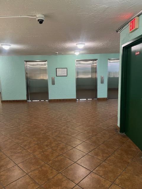 2075 SW 122nd Ave Unit 513, Miami, FL 33175 - spare room featuring elevator, baseboards, and a textured ceiling