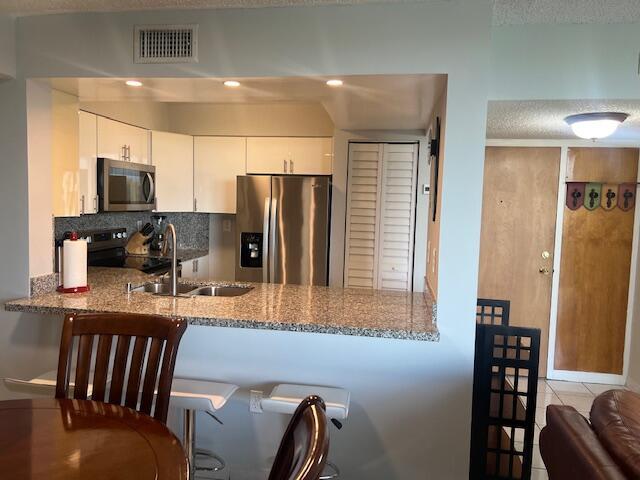2075 SW 122nd Ave Unit 513, Miami, FL 33175 - kitchen with decorative backsplash, a sink, visible vents, a peninsula, and appliances with stainless steel finishes