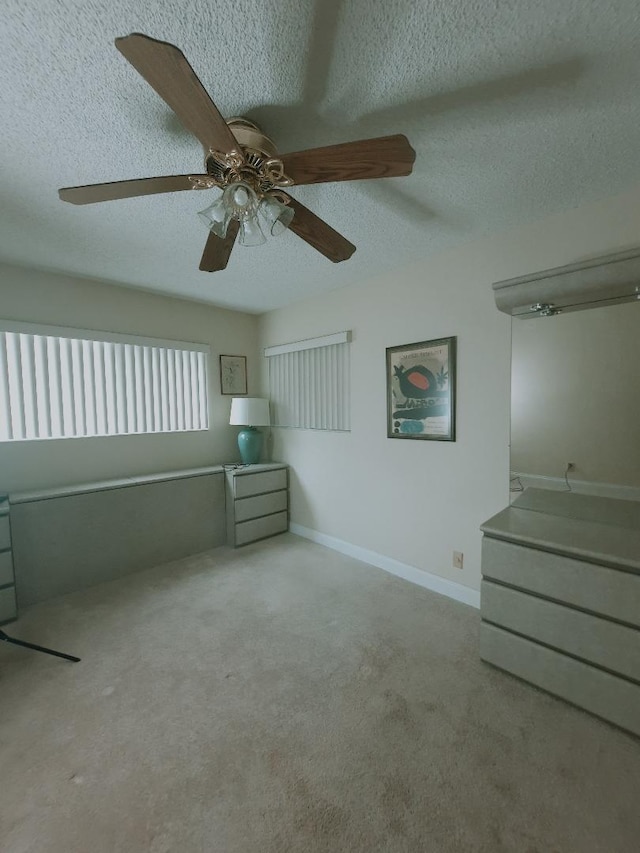 unfurnished bedroom with a textured ceiling, carpet flooring, and ceiling fan