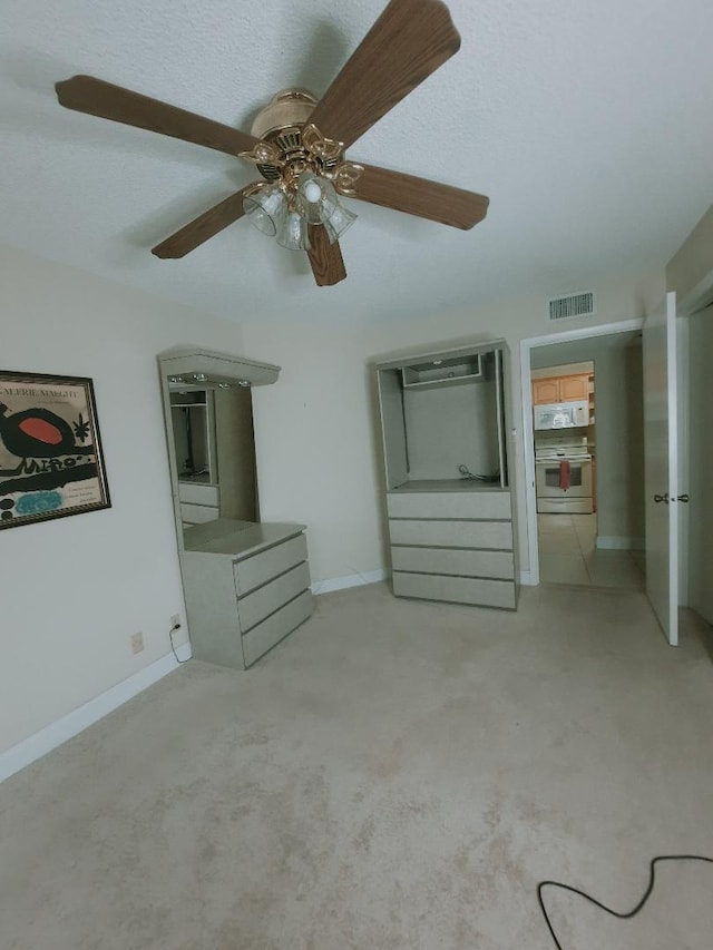 unfurnished bedroom with light colored carpet, ceiling fan, a wall unit AC, and baseboards