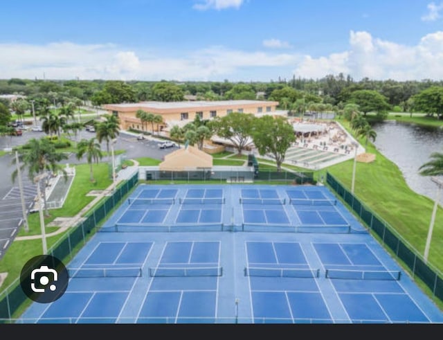 view of tennis court with fence and a water view
