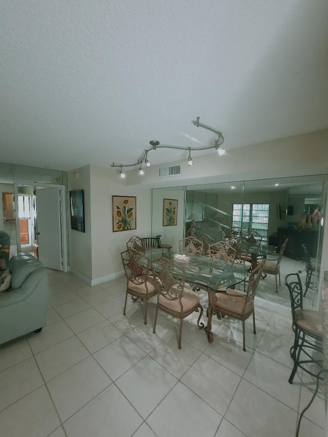 dining area featuring light tile patterned floors, plenty of natural light, a textured ceiling, and baseboards