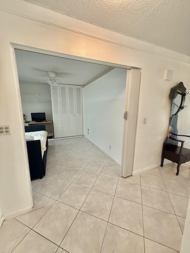 interior space with light tile patterned floors, a ceiling fan, and a textured ceiling