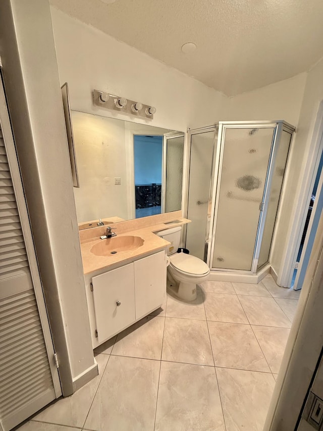 bathroom featuring tile patterned floors, toilet, a stall shower, a textured ceiling, and vanity
