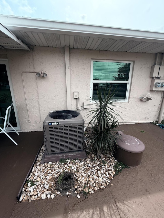 details featuring stucco siding, cooling unit, and electric meter