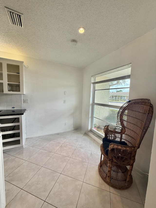 living area with light tile patterned floors, visible vents, recessed lighting, and a textured ceiling