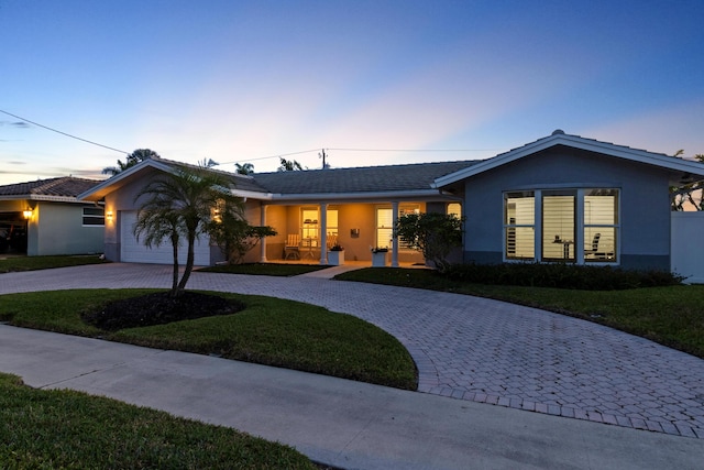 6611 NE 21st Ln, Fort Lauderdale, FL 33308 - ranch-style home featuring a garage, curved driveway, stucco siding, and a yard