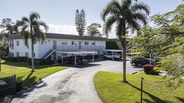 2950 SE Ocean Blvd Unit 152, Stuart, FL 34996 - view of property featuring covered parking, a front lawn, stairs, and stucco siding