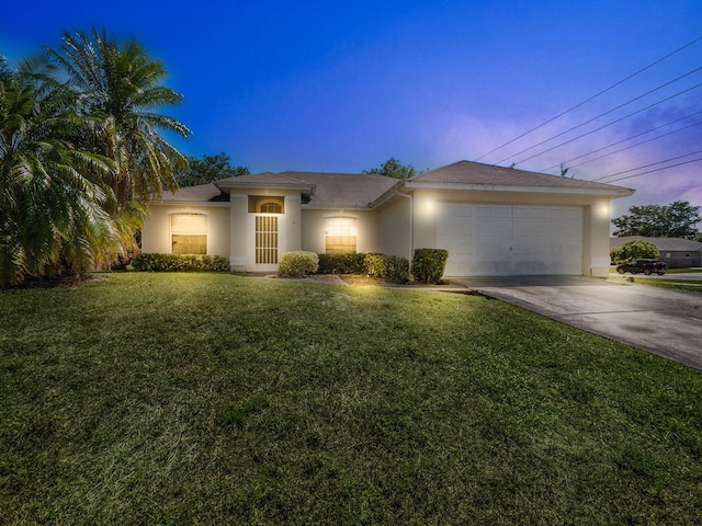 prairie-style home with stucco siding, concrete driveway, a lawn, and a garage