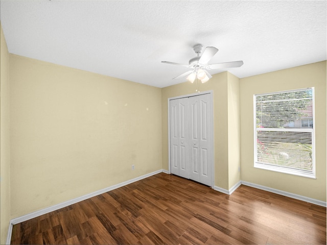 unfurnished bedroom with baseboards, wood finished floors, a closet, a textured ceiling, and a ceiling fan