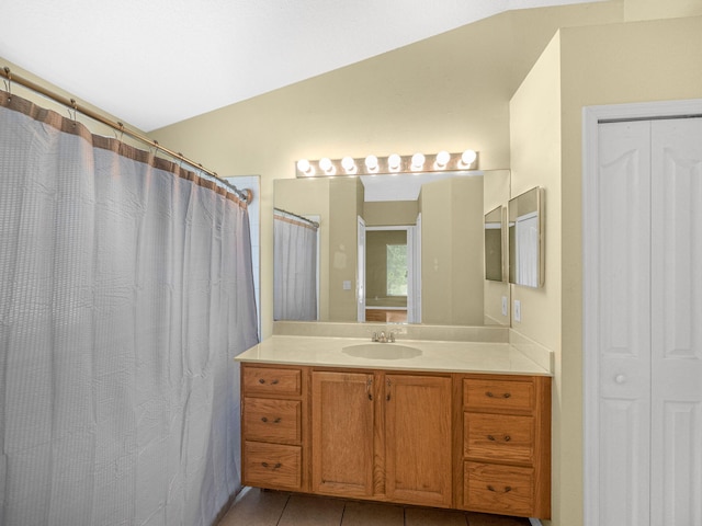 full bath with lofted ceiling, vanity, and tile patterned flooring